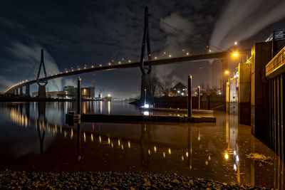 Illuminated bridge over river against sky at night