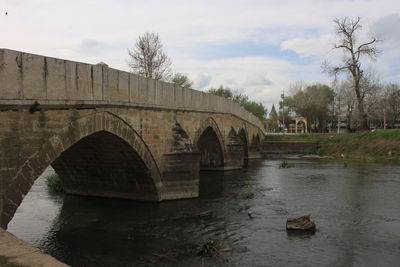 Arch bridge over river against sky