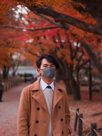 Portrait of young man standing against trees