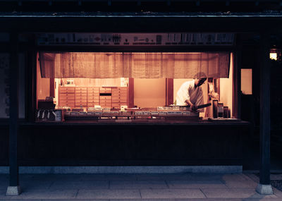 Rear view of man sitting on bench at home