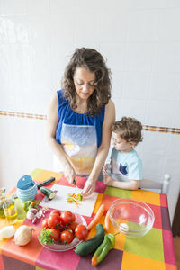 Woman preparing food while standing with son