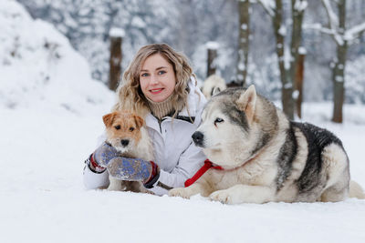 Portrait of young woman with dogs on snow