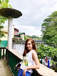 Portrait of smiling young woman standing against trees