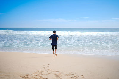 Rear view of man on beach against sky