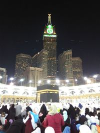 Group of people at illuminated building against sky at night