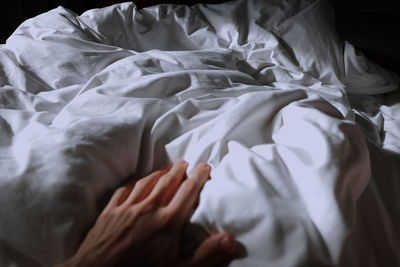 Close-up of human hand on bed