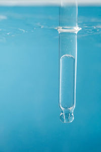 Pipette with cosmetic product in water with bubbles.