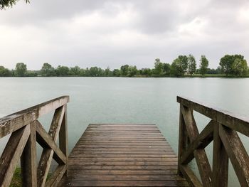 Wooden jetty on pier over lake against sky