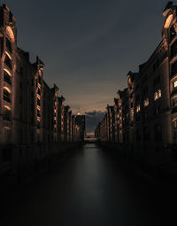 Canal amidst buildings against sky at night