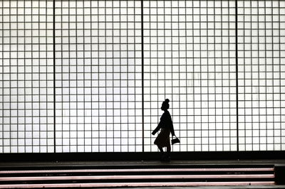 Silhouette man standing against chainlink fence