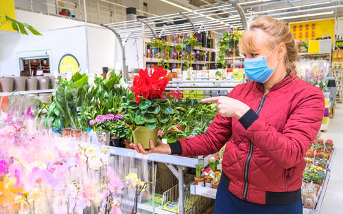 Portrait of young woman standing by plants