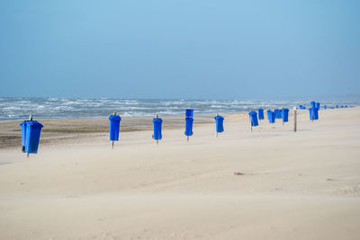 Wooden posts on beach against clear blue sky