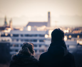 Rear view of women against sky during sunset in city