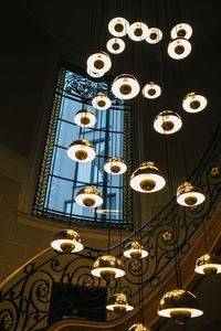 Low angle view of illuminated pendant lights hanging on ceiling in building