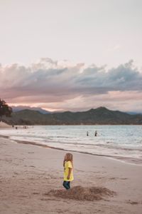 Rear view of people on beach against sky during sunset