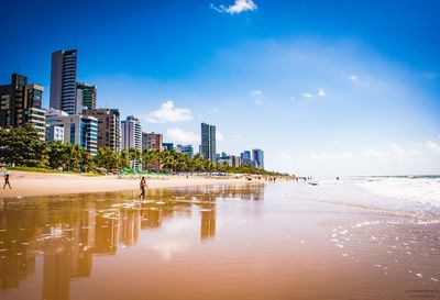 City buildings by sea against sky