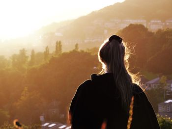 Rear view of woman against trees during sunset