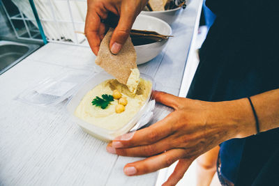 Midsection of person having hummus with nachos