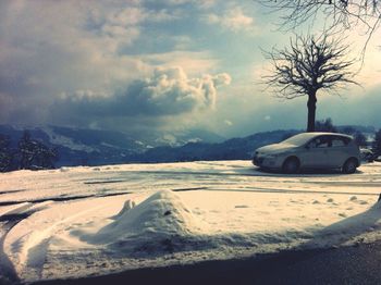 Scenic view of snow covered mountains against cloudy sky