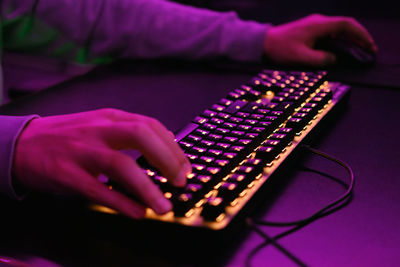 Close-up of a hand on a keyboard in neon color. selective focus