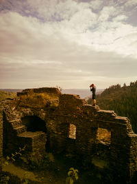 Man standing on rock against sky