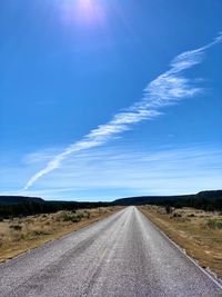 Empty road amidst landscape against sky