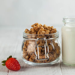 Homemade granola, milk in a jar and strawberries on a wooden background. 