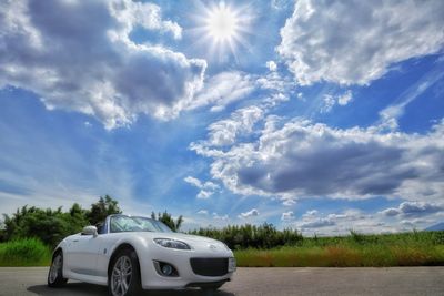 Cars on road amidst field against sky