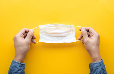 Midsection of person holding paper against yellow background