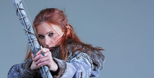 Portrait of young woman holding bow and arrow