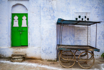 Old cart on footpath against wall