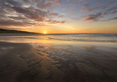 Scenic view of beach against sky during sunset