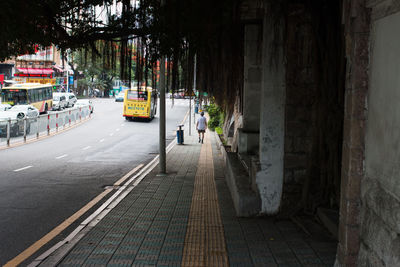 Rear view of man walking on sidewalk in city