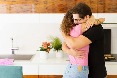 Side view of young woman standing against wall