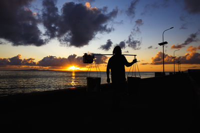 Silhouette man standing on beach against sky during sunset