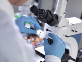 Cropped hands of male scientist holding microscope slide with blood in laboratory