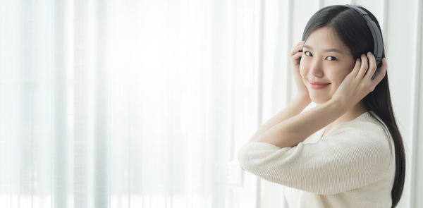 Portrait of woman standing against curtain