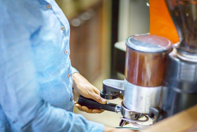 Close up barista is grinding freshly roasted by coffee grinder make beans into a powder.