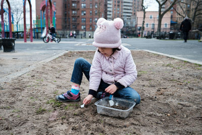 Girl digging in the dirt on the playground on a foggy fall day