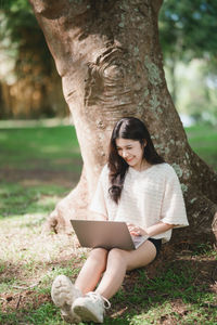 Young woman sitting on tree