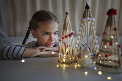 Cute girl looking at illuminated christmas ornaments