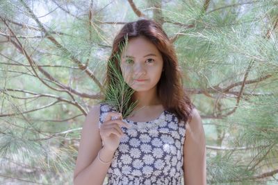 Portrait of beautiful woman standing against plants