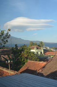 Houses in village by town against sky