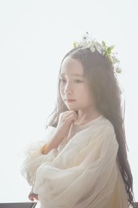 Portrait of young woman standing against white background