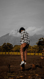 Rear view of person standing on land against sky