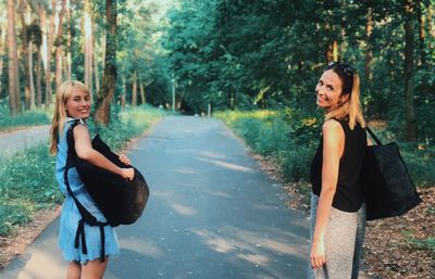 Portrait of smiling young woman against trees