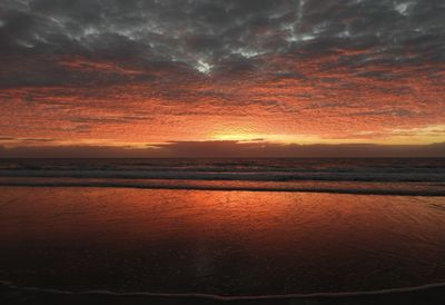 Scenic view of sea against dramatic sky during sunset