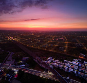 High angle view of illuminated city buildings against sky during sunset