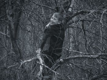 Portrait of boy feeding on tree in forest