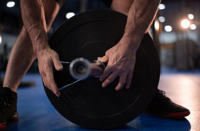 Cropped senior athlete putting spring collar on barbell